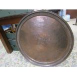 A large copper charger with eastern hammered design 82cm diameter