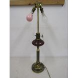 A brass based lamp with cranberry glass globe detail, no shade