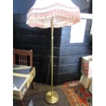 A brass base standard lamp with vintage pink shade