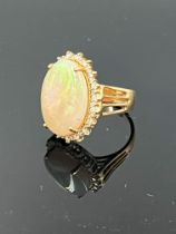 A opal and diamond cluster ring, the oval is a full pebble stone opal approx. 15 carat claw set