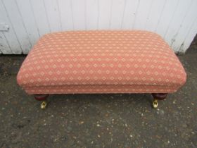 Upholstered footstool on castors