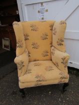 Upholstered wing back chair on castors