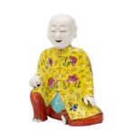 A Chinese famille rose figural joss stick holder of a seated laughing boy,