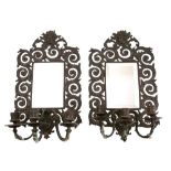 A pair of bronzed metal and mirrored girandoles of arched outline,