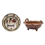 Two Persian bowls, one with lug handles and notched rim set on three peg feet under brown glazes,