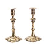 A pair of early 18th century brass candlesticks with urn-shaped sconces, on knopped stems,