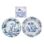 Two English blue and white delftware plates and a similar tile both plates painted with a Chinese