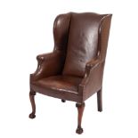 A studded leather wing armchair in George II taste, early 20th century; with outscrolled arms,