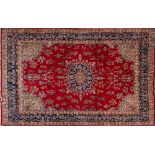 A Kirman Carpet, the red field with a central arabesque oval indigo and pastel blue medallion,