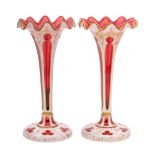 A pair of Bohemian ruby and white overlay glass lustre stands with frilled rims,