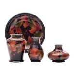 Three Moorcroft vases and a plate each tube lined in the Pomegranate pattern in red, purple,