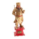A gilt and polychrome decorated Chinese warrior figure holding a staff in his right hand,