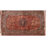 A Qum silk rug, the red field with a design of animals, palmettes and floral foliage,