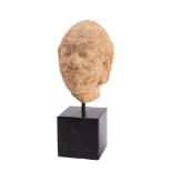 An Indian carved sandstone head of a moustachioed man with shaved head, furrowed forehead,