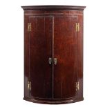 A George III mahogany bow fronted hanging corner cabinet,