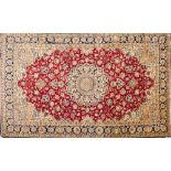 A Qum part silk carpet:, the red cartouche field with a central indigo,