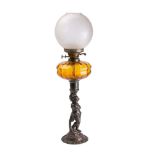 A Victorian cast iron oil lamp the amber glass reservoir mounted on a column with putti on a domed