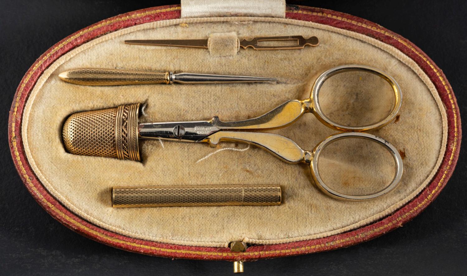 An early 20th century Asprey sewing companion, comprising a needle case, stamped '9CT', a thimble,