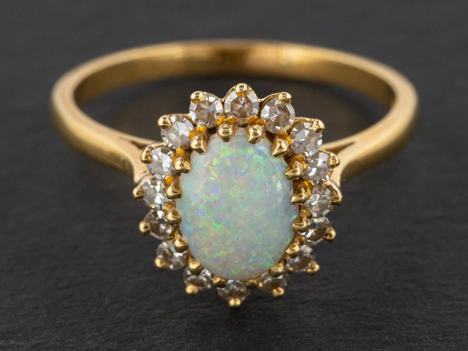 An 18ct gold, oval, cabochon-cut opal and single-cut diamond cluster ring,