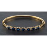 An oval, mixed-cut sapphire and round, brilliant-cut diamond hinged bangle,