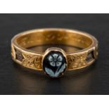 A late Victorian, gold, mourning ring, set with a carved sardonyx depicting a forget-me-knot,