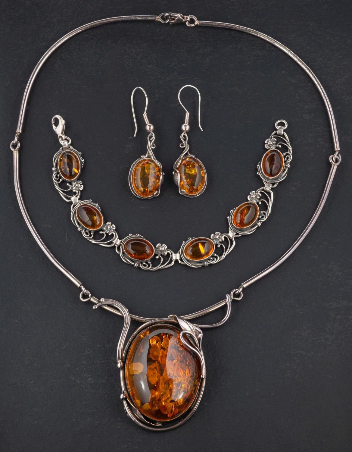 A oval amber necklace, bracelet and pair of earrings, with applied floral and foliate decoration,