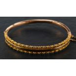 A late Victorian, 9ct gold, hinged bangle, with rope-work and ball decoration to borders,