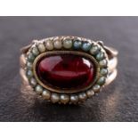 A Georgian mourning ring, the foiled back garnet with seed pearl surround,
