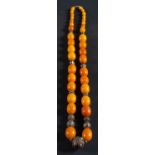 A graduated amber bead necklace, with ropework and foliate decorated spacers,