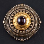 A 15ct gold, late Victorian, Etruscan Revival style, cabochon-cut garnet brooch, diameter ca. 3.