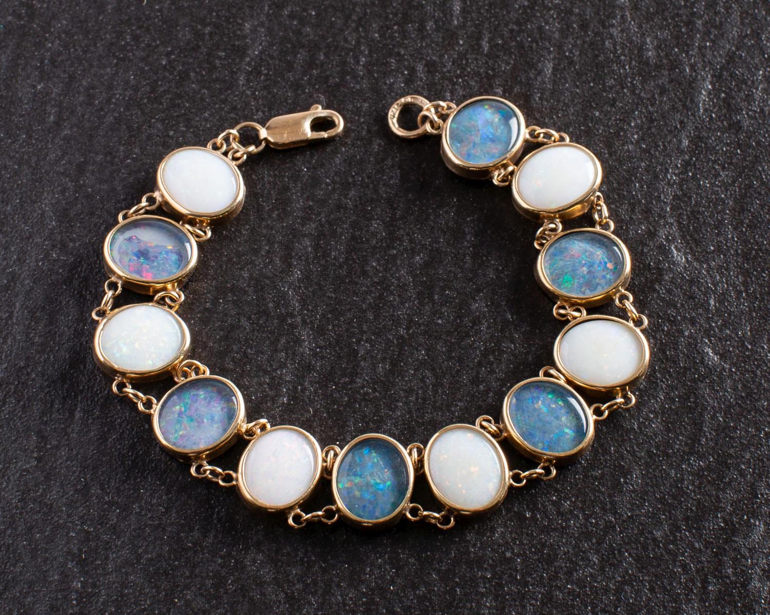 A 9ct gold, oval, cabochon-cut white opal and black opal triplet bracelet,