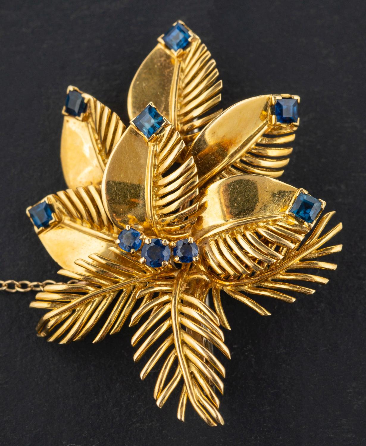 An 18ct gold, round, mixed and square step-cut sapphire floral brooch, with hallmarks for London,