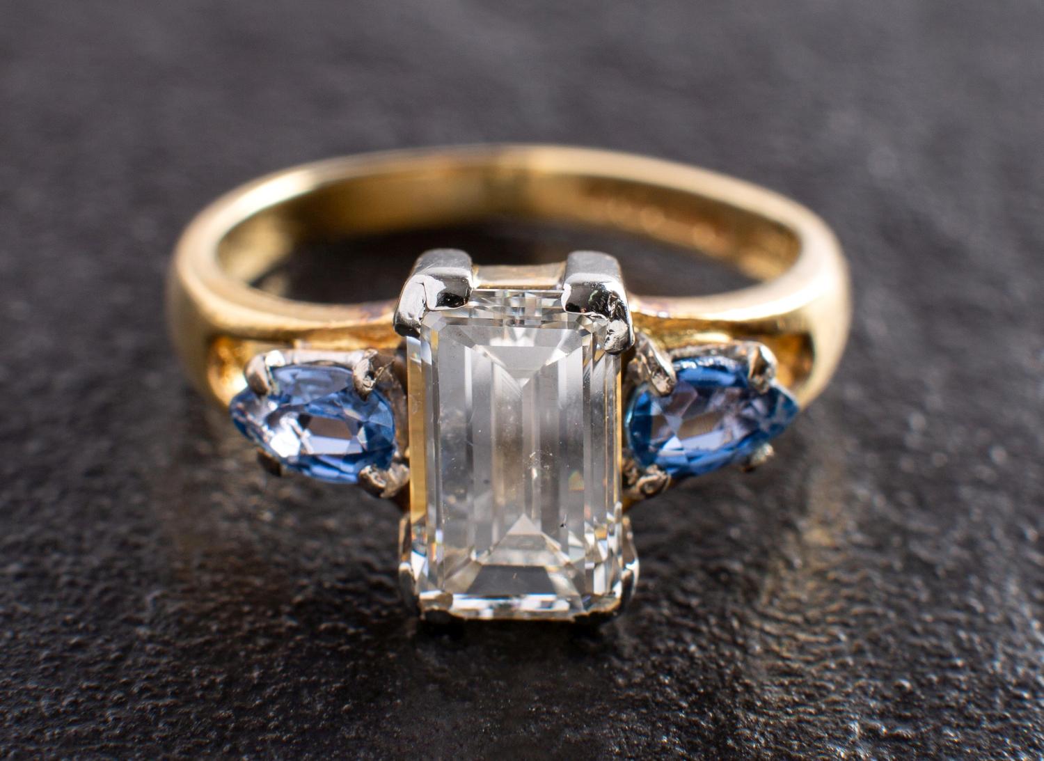 An 18ct gold, octagonal, step-cut diamond and pear-shaped sapphire three-stone ring,