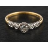 A round, brilliant-cut diamond single-stone ring, the diamond within a heart-shaped mount,
