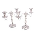 A pair of silver plated twin branch candelabra with scrolling branches terminating in urn-shaped