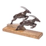 An Art Deco bronze patinated metal group of two leaping gazelles mounted on a polished marble base,