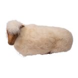 John Neusinger, a carved wood and sheepskin covered foot stool: as a recumbent sheep, 73cm long.