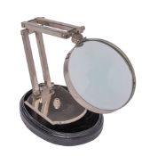 A chrome plated angle-poise desk magnifying glass with 12cm circular lens mounted on an ebonised