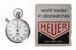 A vintage Heuer Trackmate stopwatch in original box with warranty booklet and unused Heuer sticker.
