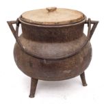 A bronze twin-handled cauldron of bag shape with iron swing handle and tripod feet,