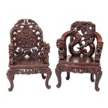 Two similar Chinese carved and stained hardwood elbow chairs,