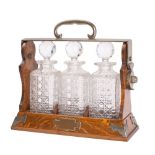A Victorian oak and silvered metal mounted three-decanter tantalus, late 19th century,