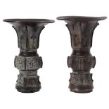 A matched pair of Chinese bronze vases, Gu with flared necks,