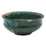 A Chinese green glazed pottery bowl with indented rim and beaded band below, possibly Tang Dynasty,