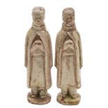 A pair of Chinese pale celadon glazed terracotta funerary figures each modelled standing with