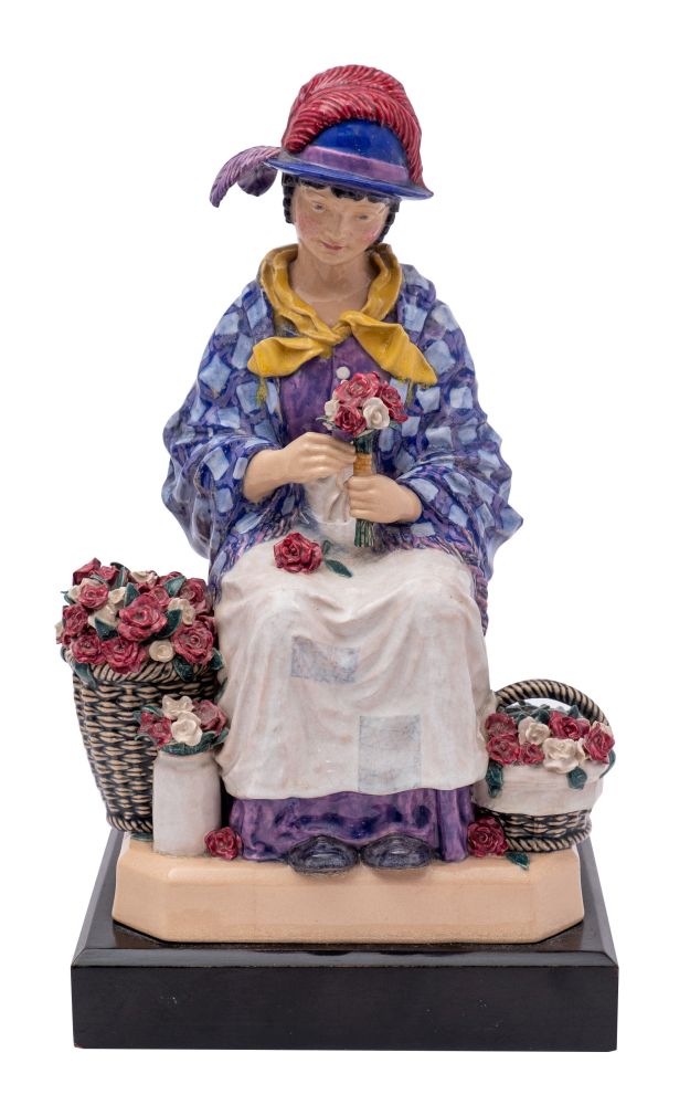 A Harry Parr pottery figure of a flower seller modelled as a girl seated on a large basket and
