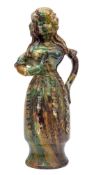 A French pottery figural jug in the form of a girl, decorated in mottled green,