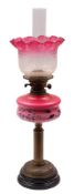 An Edwardian cranberry glass and brass paraffin lamp, circa 1900, with flared,