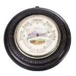 An Edwardian ebonised aneroid barometer the round dial with a landscape scene to the centre,