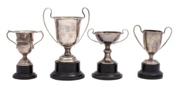Four small silver twin-handled trophy cups (various dates and makers) each with an ebonised plinth,